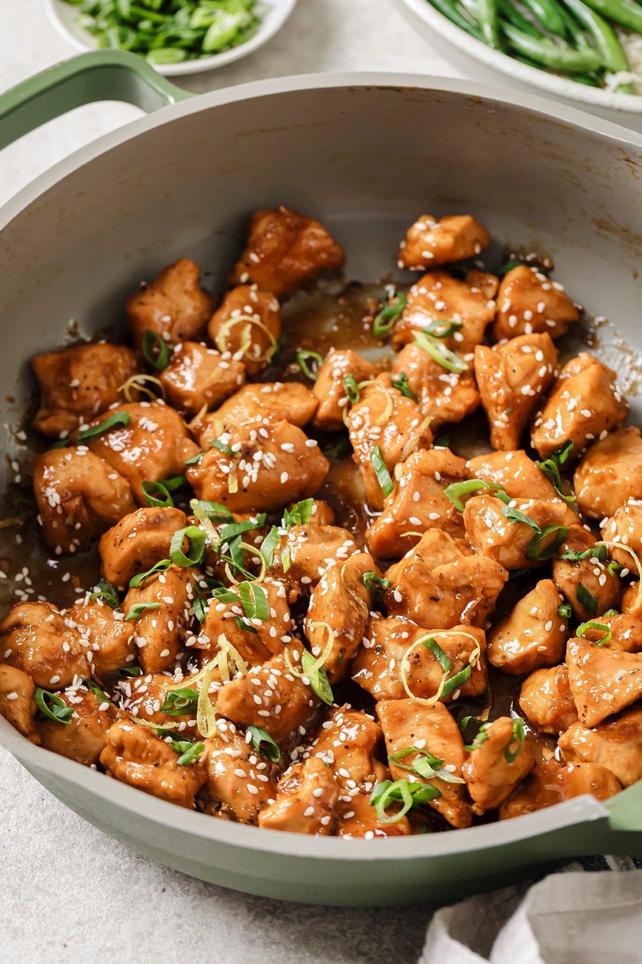 Gluten free chinese lemon chicken in a pan topped with green onion and lemon zest