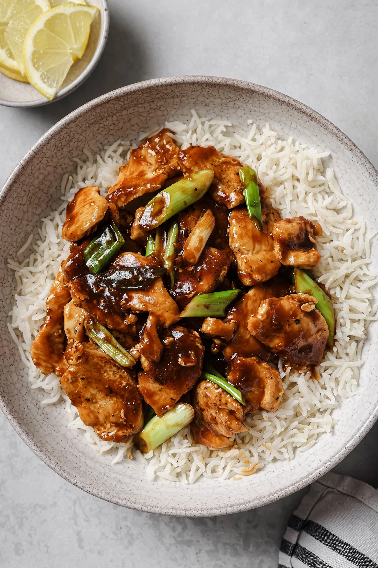 Gluten free mongolian chicken with green onions on a bed on white rice.