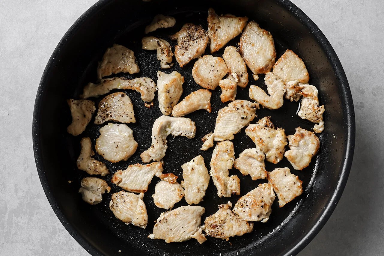 Cooked cubed chicken in a pan.