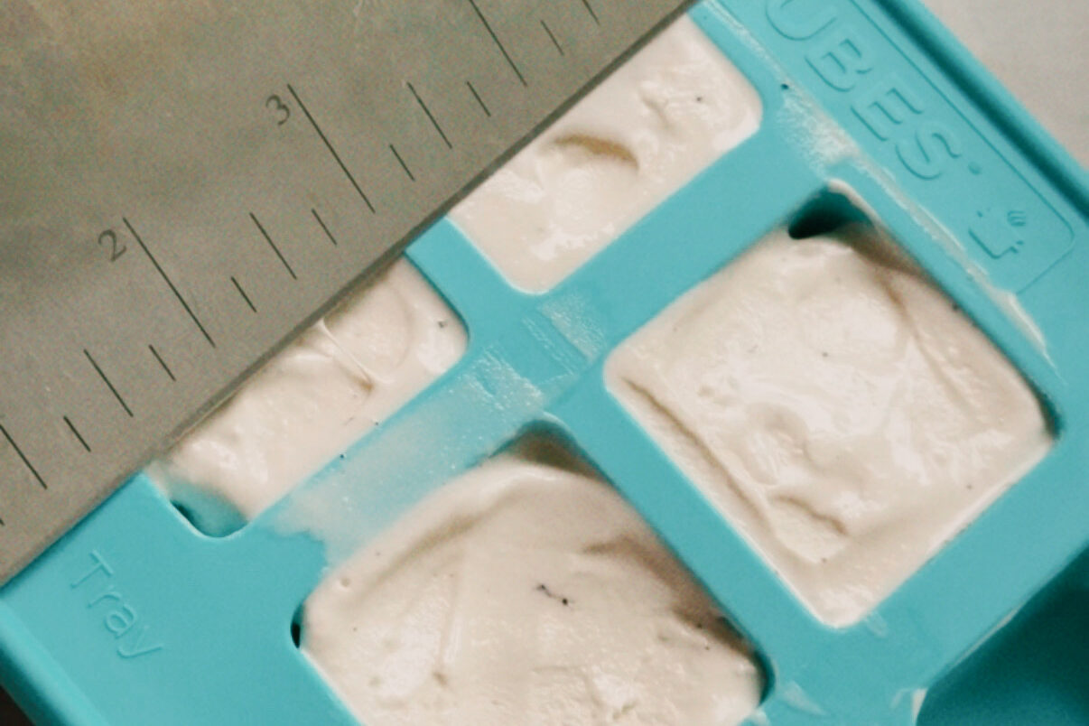 The silicone molds filled with ice cream being leveled off.