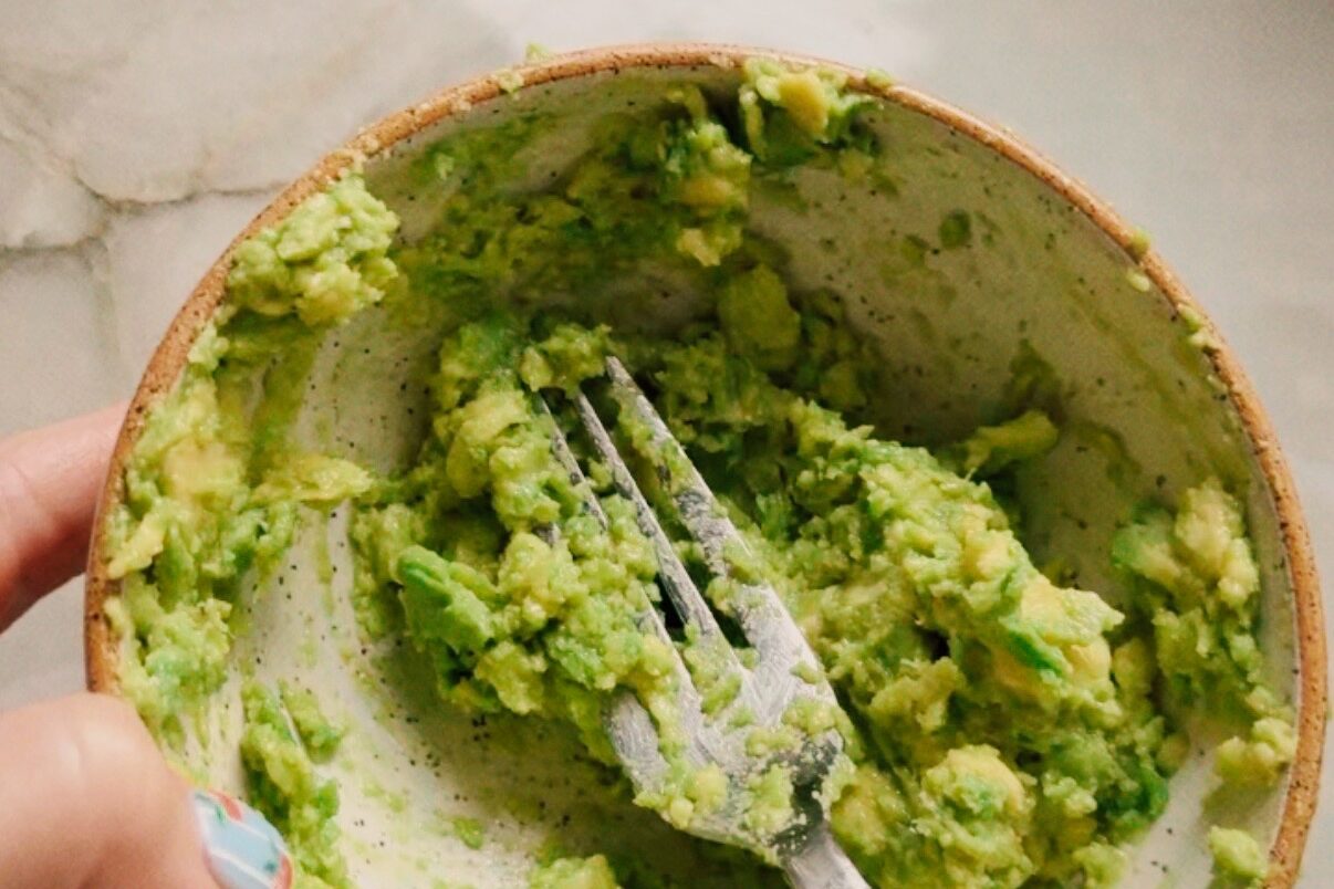Mashed avocado in a bowl with a fork