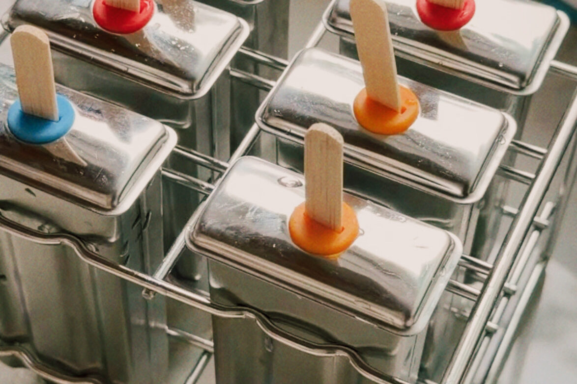 The popsicle molds filled and topped before freezing.