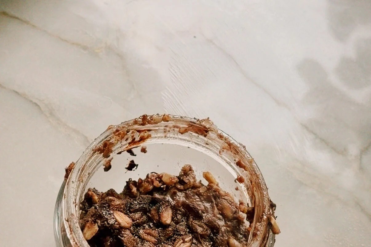 A glass jar with the baked oats layer added to it.