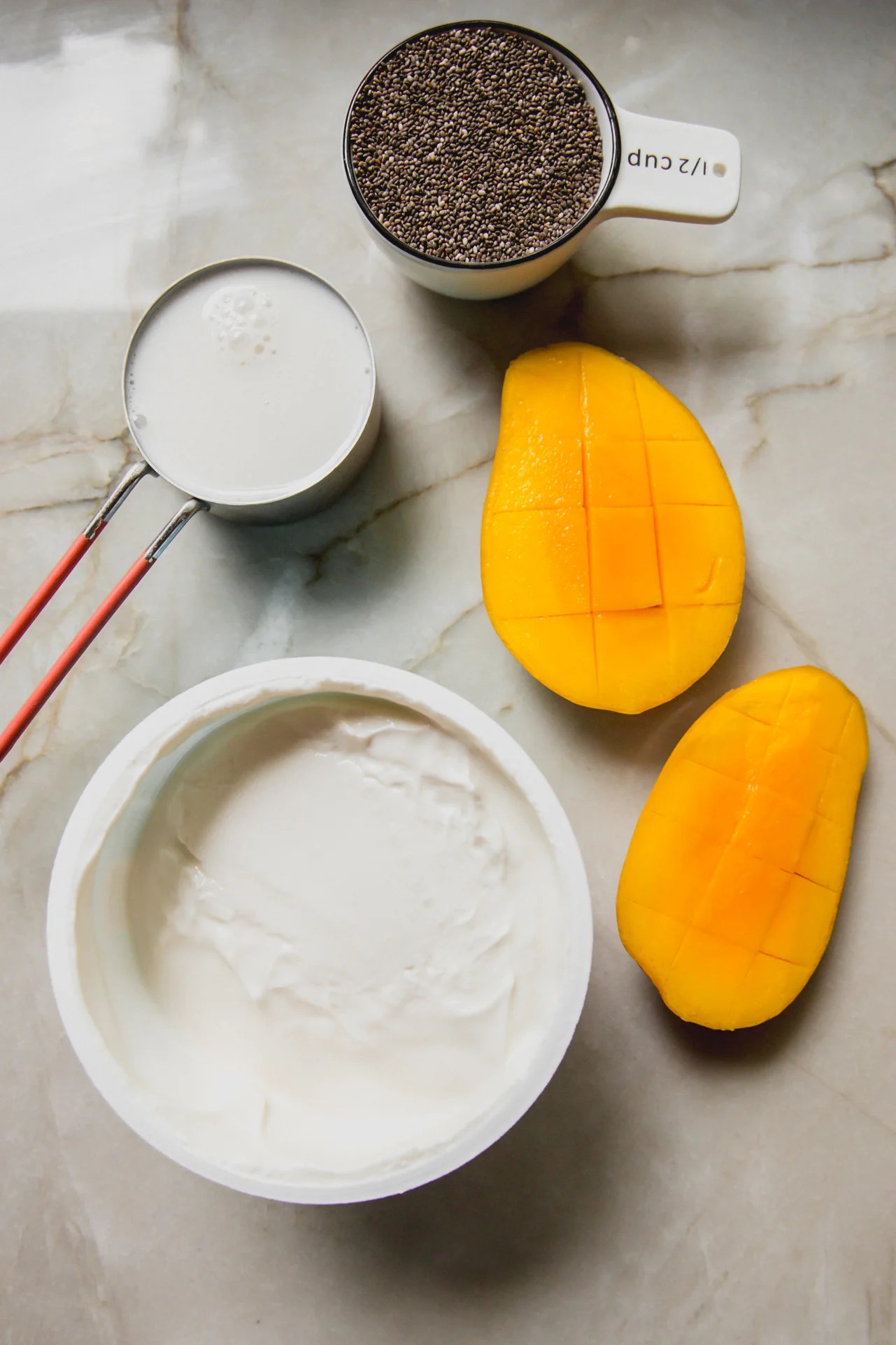 Mango chia pudding ingredients on a marble counter