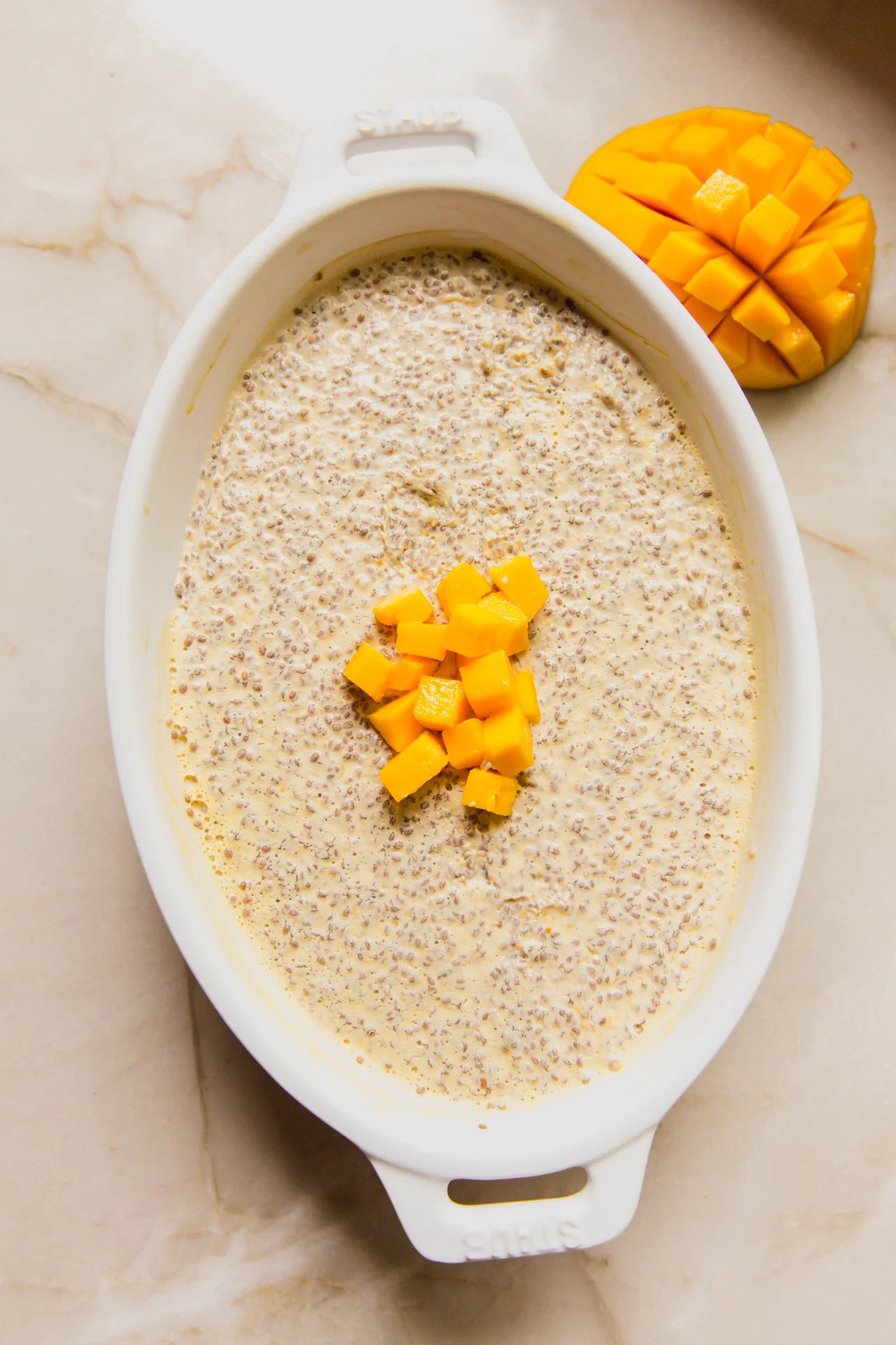 Mango chia pudding in a large white baking dish topped with extra diced mango