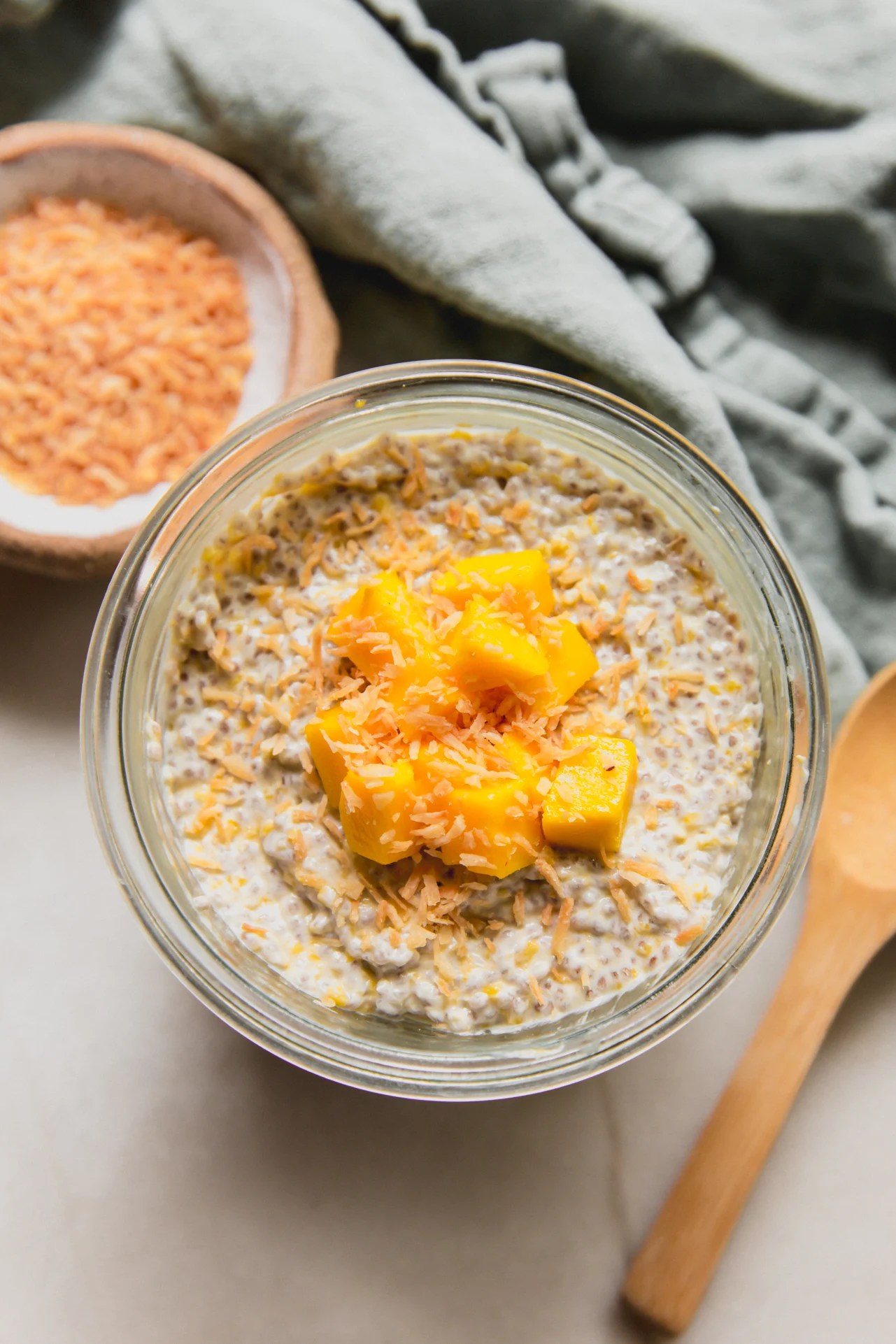 Mango chia pudding in a cup topped with diced mango and toasted coconut