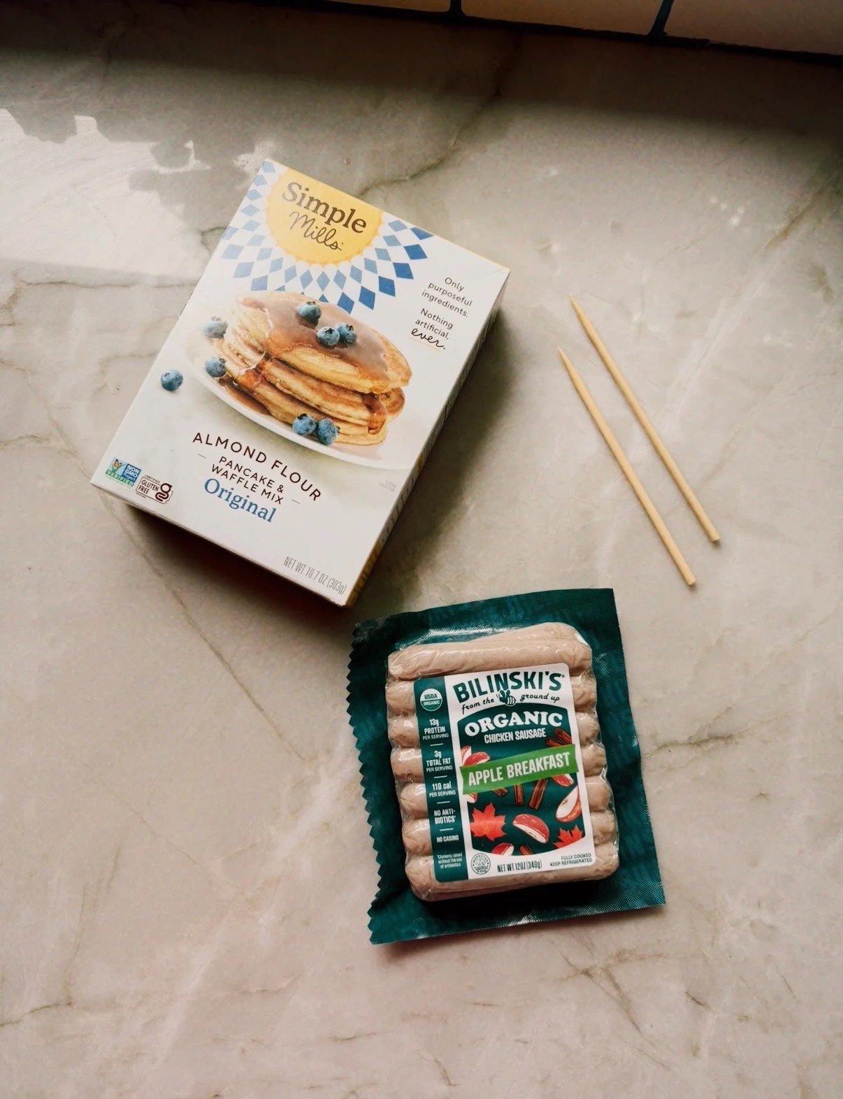 A package of chicken apple sausages and pancake mix on a counter before cooking.