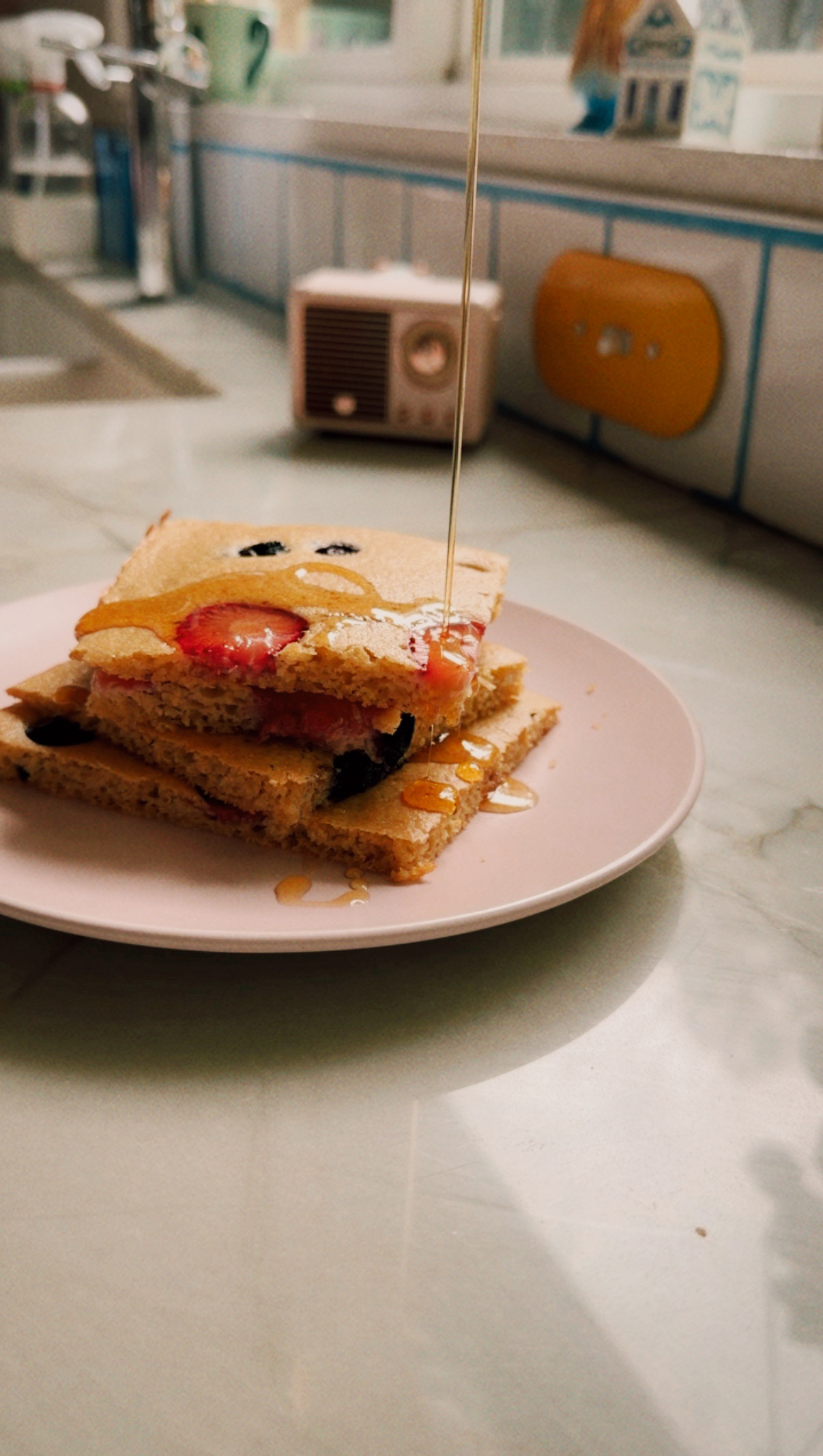 A stack of sheet pan pancakes with maple syrup being poured over