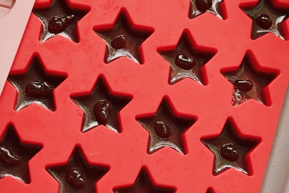 The star mold with the grape jam dotting each star mold of apple gelatin.
