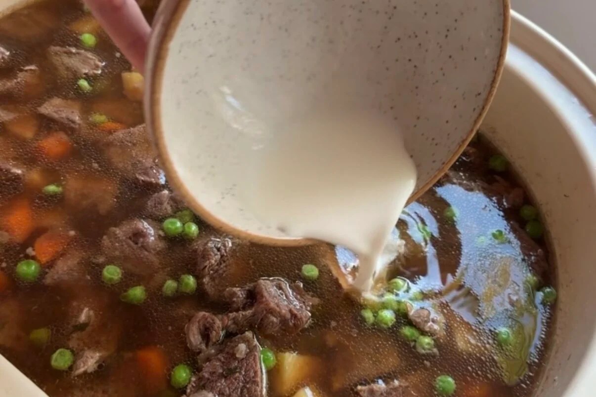 arrowroot starch slurry being poured into crock pot beef stew