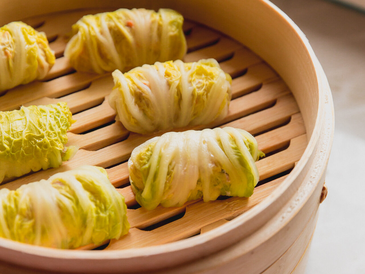 Several cabbage roll dumplings in a steamer.