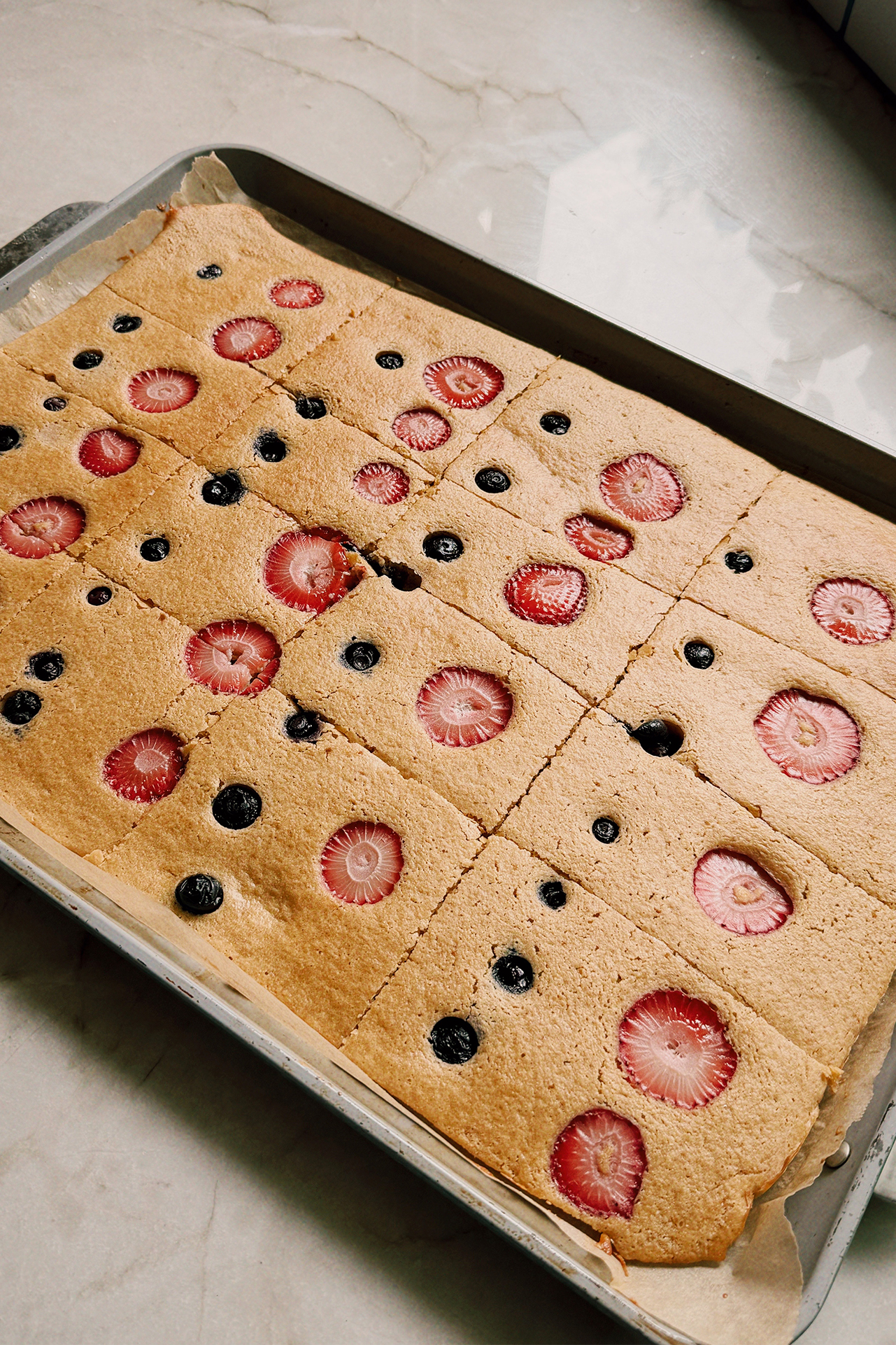 Sheet pan pancakes topped with berries on a large sheet pan