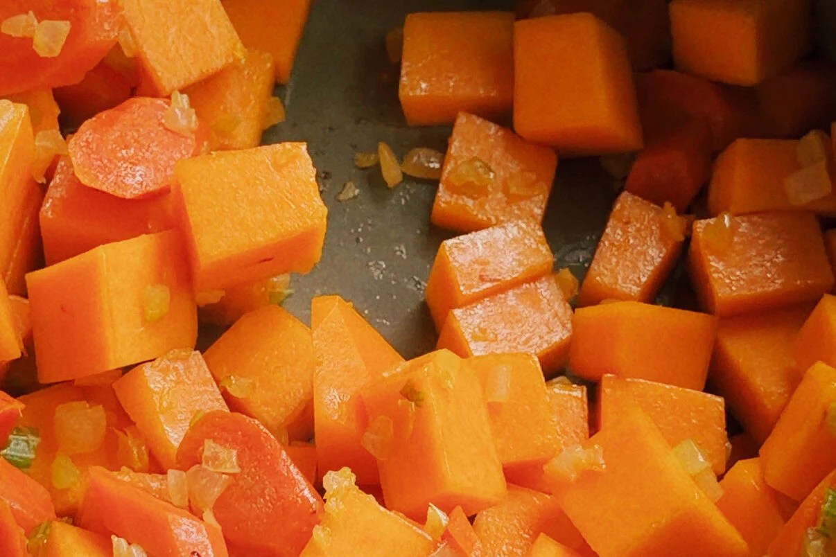 Butternut squash and garlic sauting in a pot.