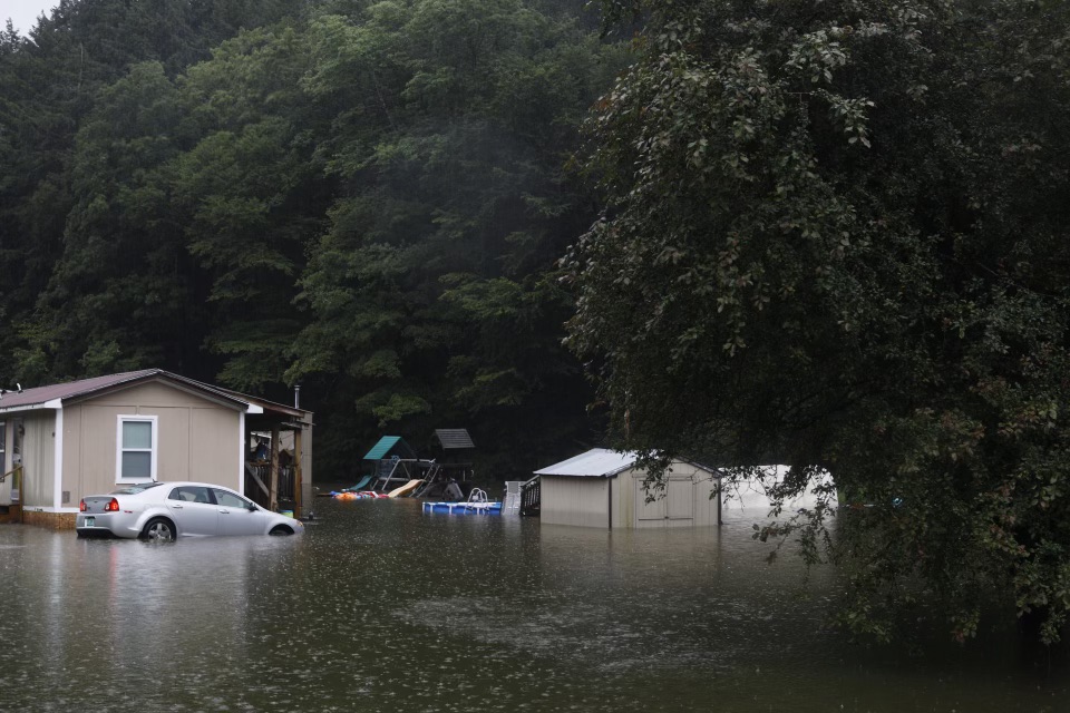 a car is parked in a flooded area near a house.