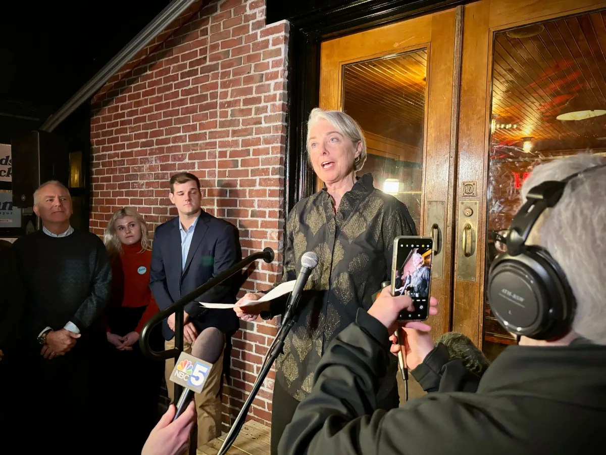 A woman speaking in front of microphones