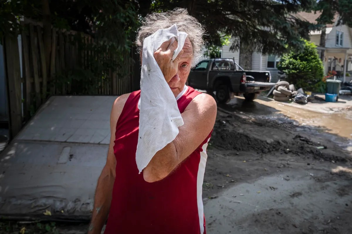 a person in a red shirt is holding a towel in front of a house.