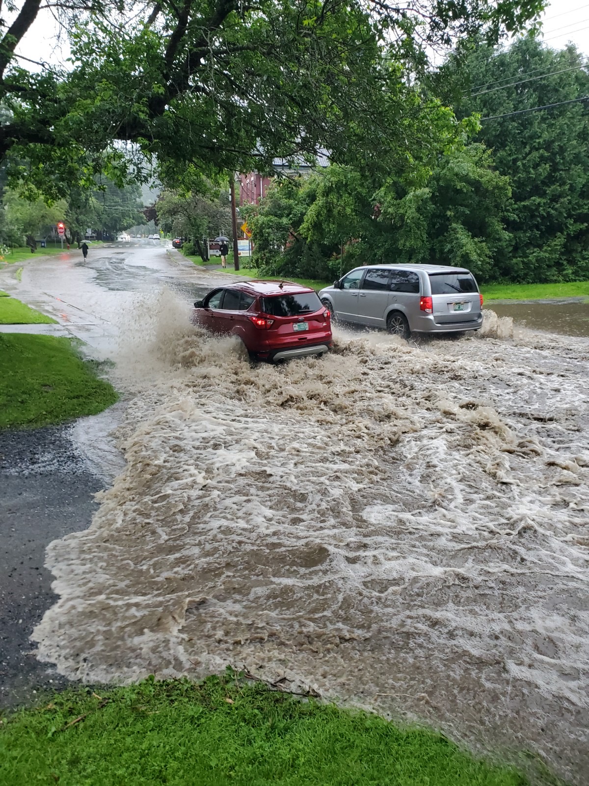 two cars driving through a flooded street.