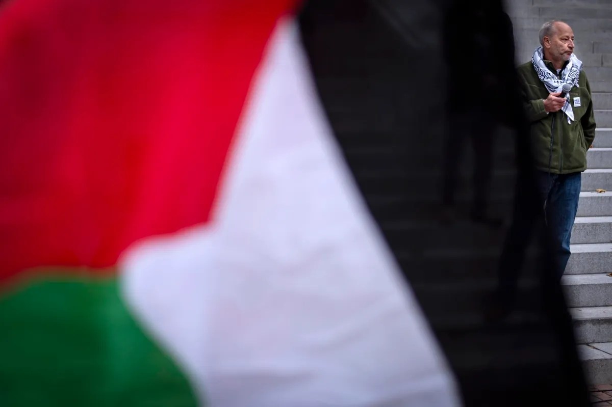 A man holds a palestinian flag in front of steps.
