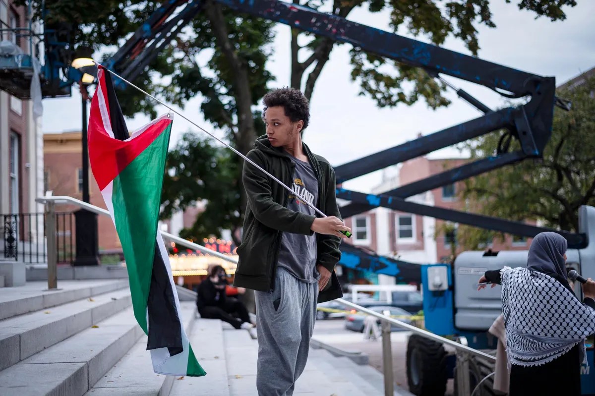 A man holding a palestinian flag on the steps of a building.