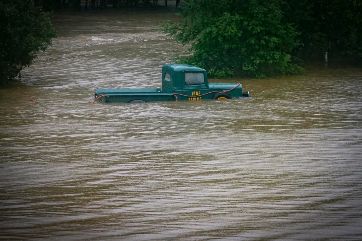 a green truck in a flooded river.