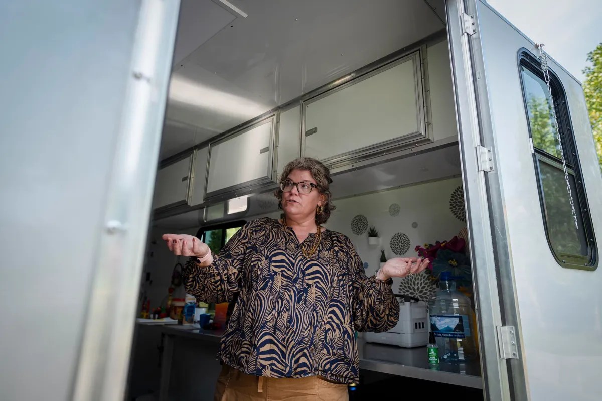 A woman standing in the kitchen of a rv.