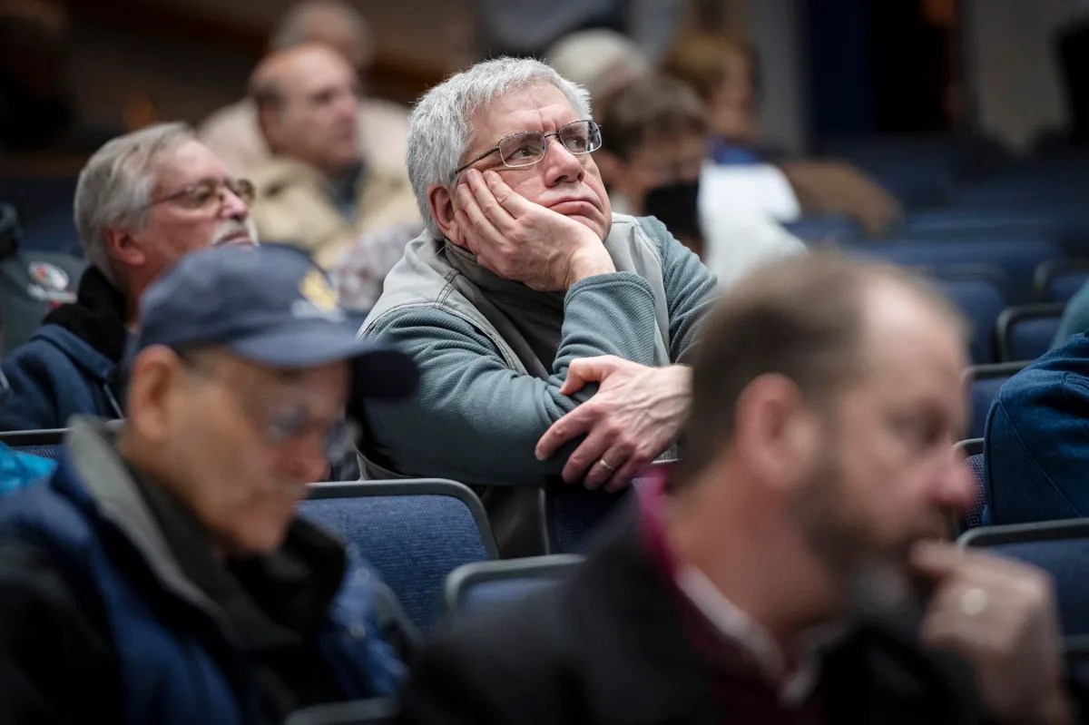 A man sits in the audience at a meeting.