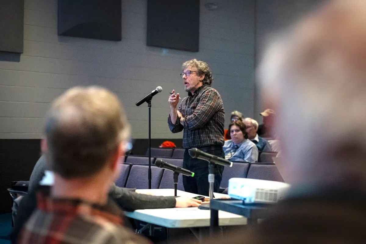 A man speaking into a microphone in front of an audience.