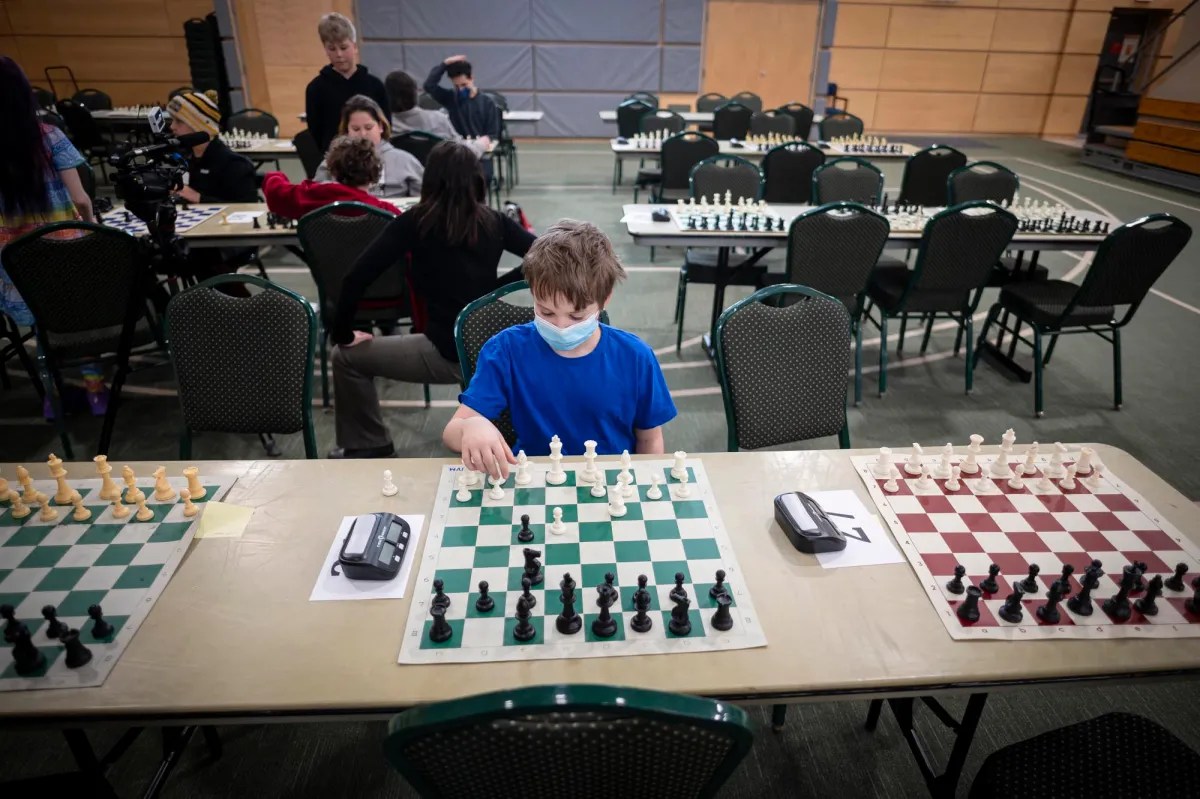 a child sitting at a table playing chess.