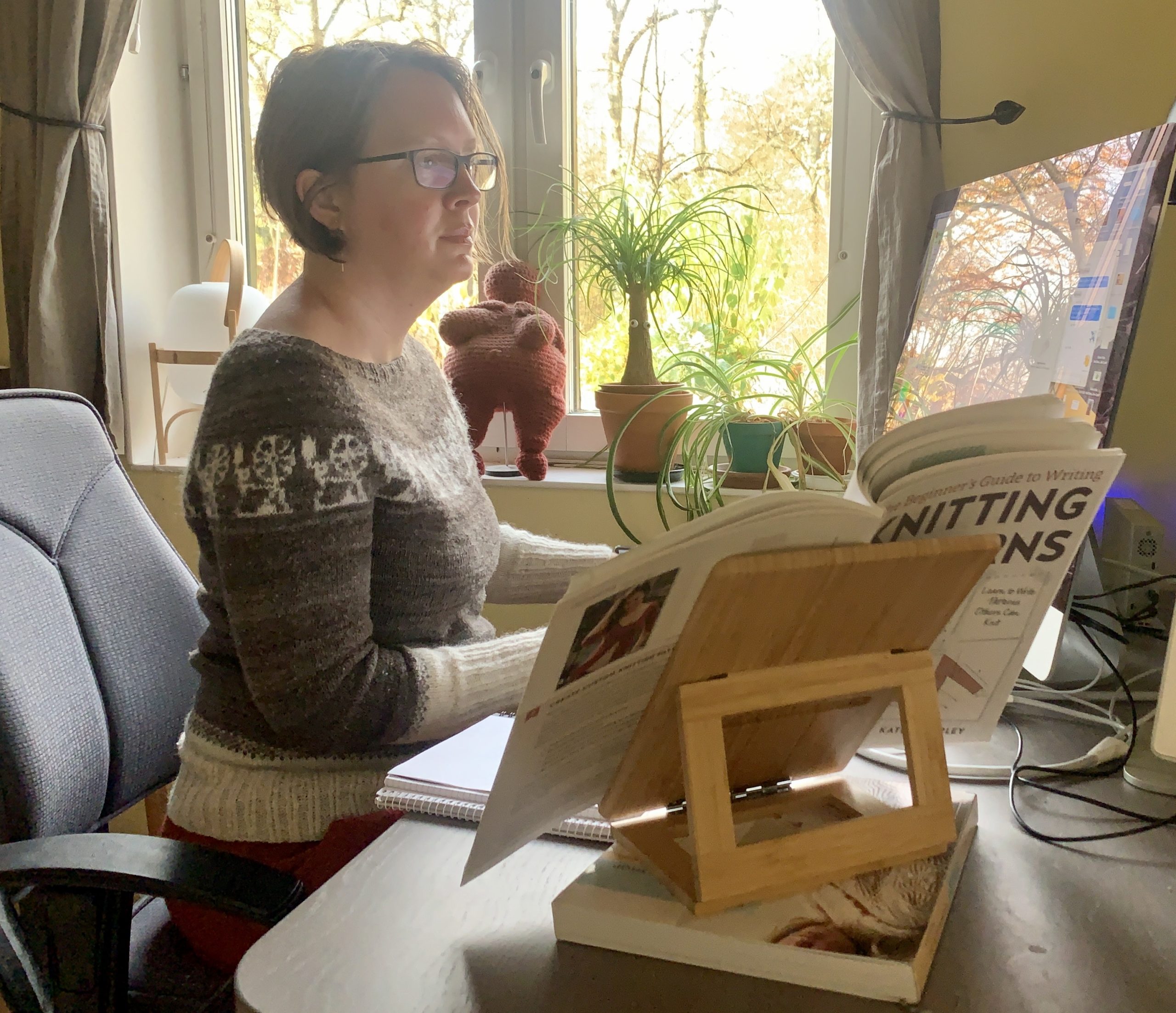 A woman working on a computer by an office desk.