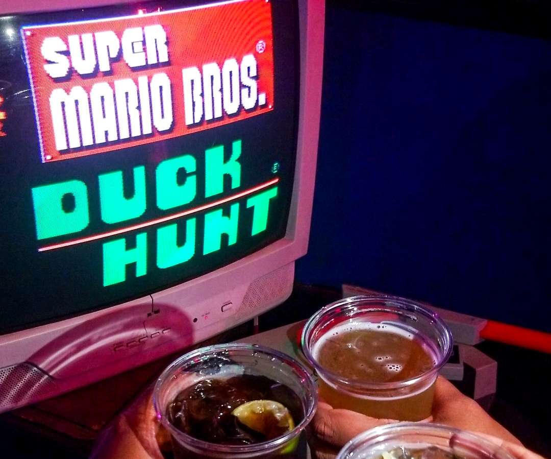 drinks in front of a small computer screen with the name super mario bros on it. 