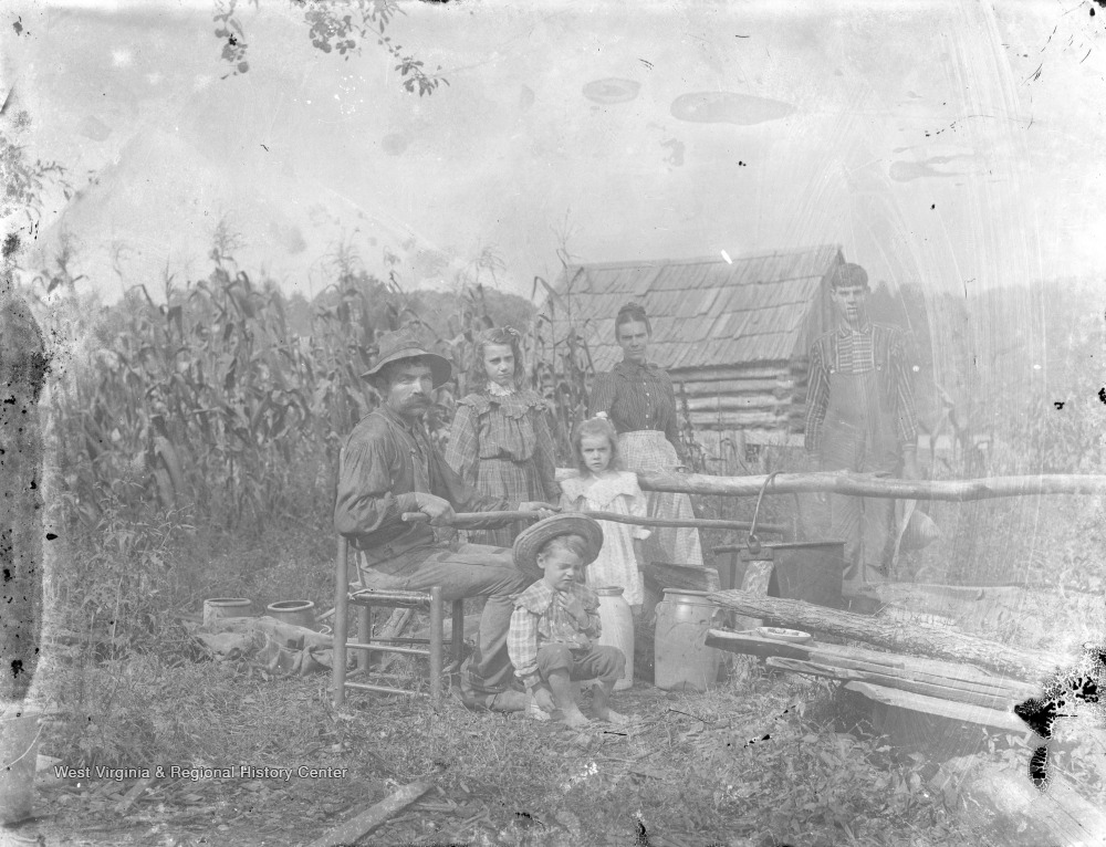 Farmer and His Family Stirring Large Pot Next to Cornfield West
