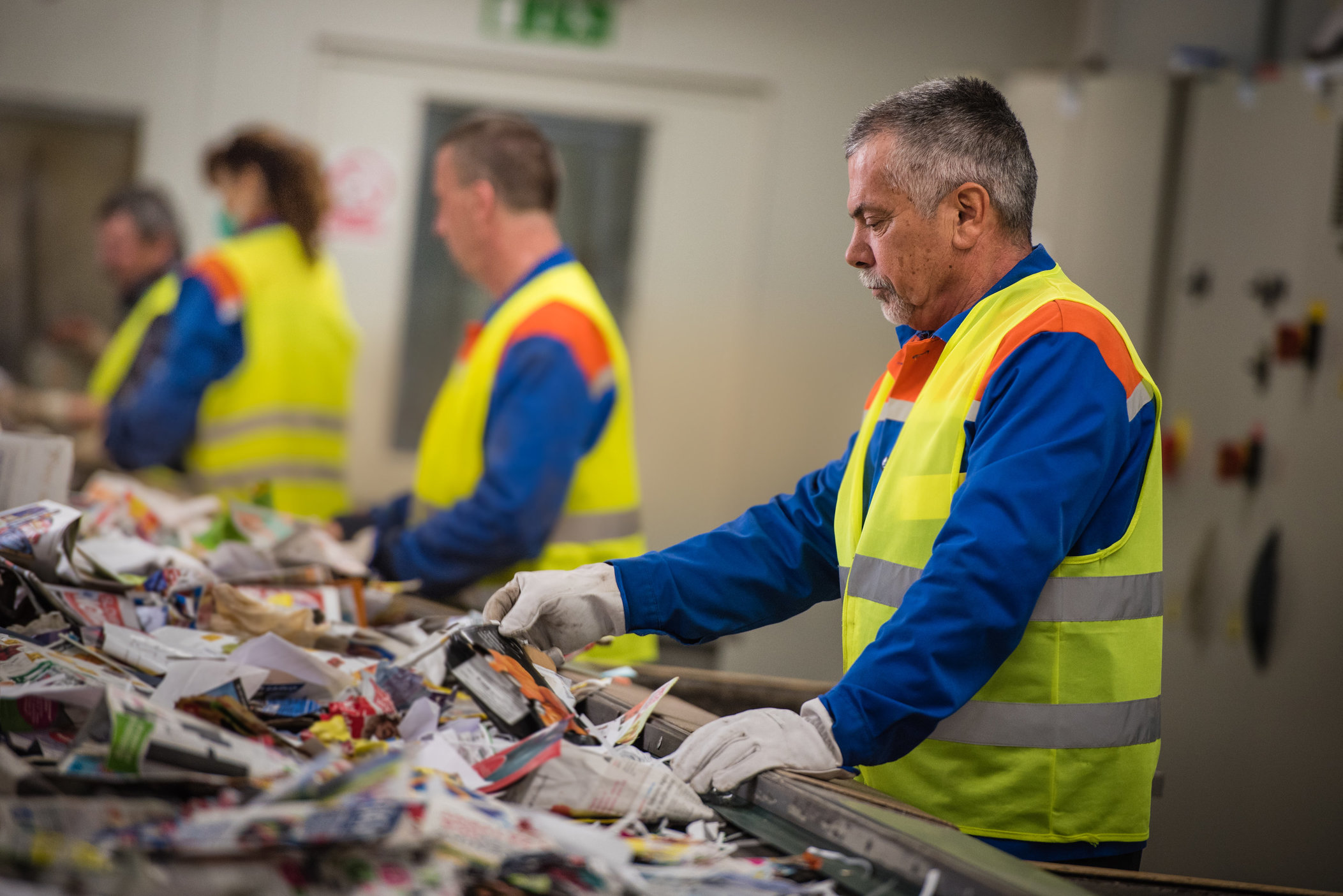 Group of workers sorting papers at recycling plant AAA Labor