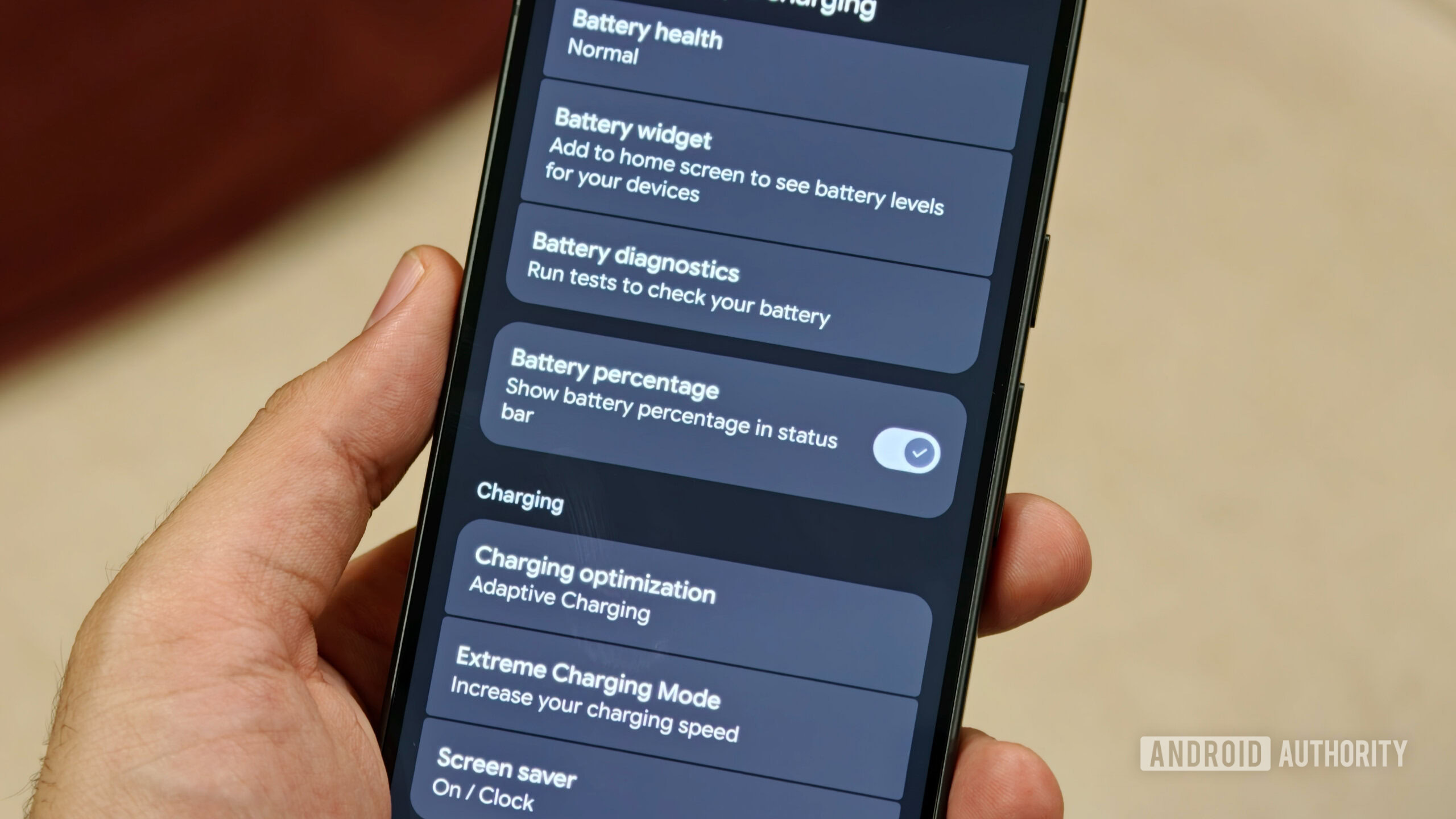 pixel 11 battery percentage toggle Hand holding Pixel 11 with battery percentage toggle enabled in settings