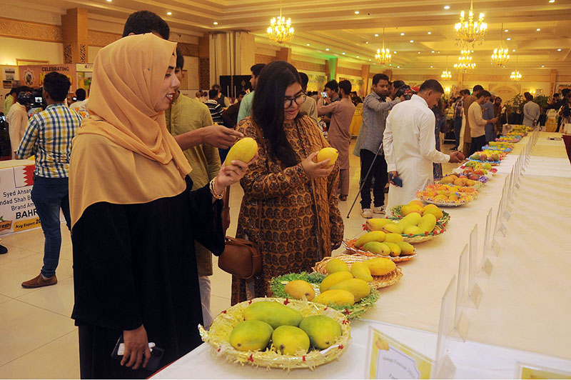 Girls viewing the displayed various varieties of mangoes during three