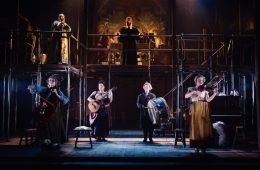 A stage view of the entire cast playing various instruments.