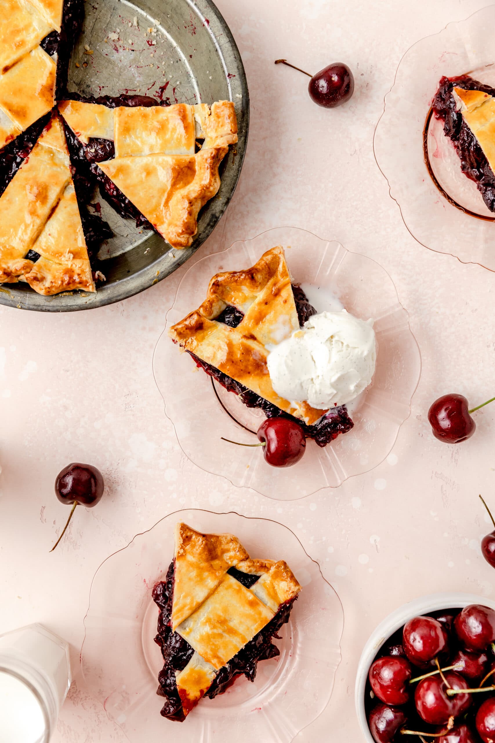 slices of cherry pie on plates with ice cream on top 