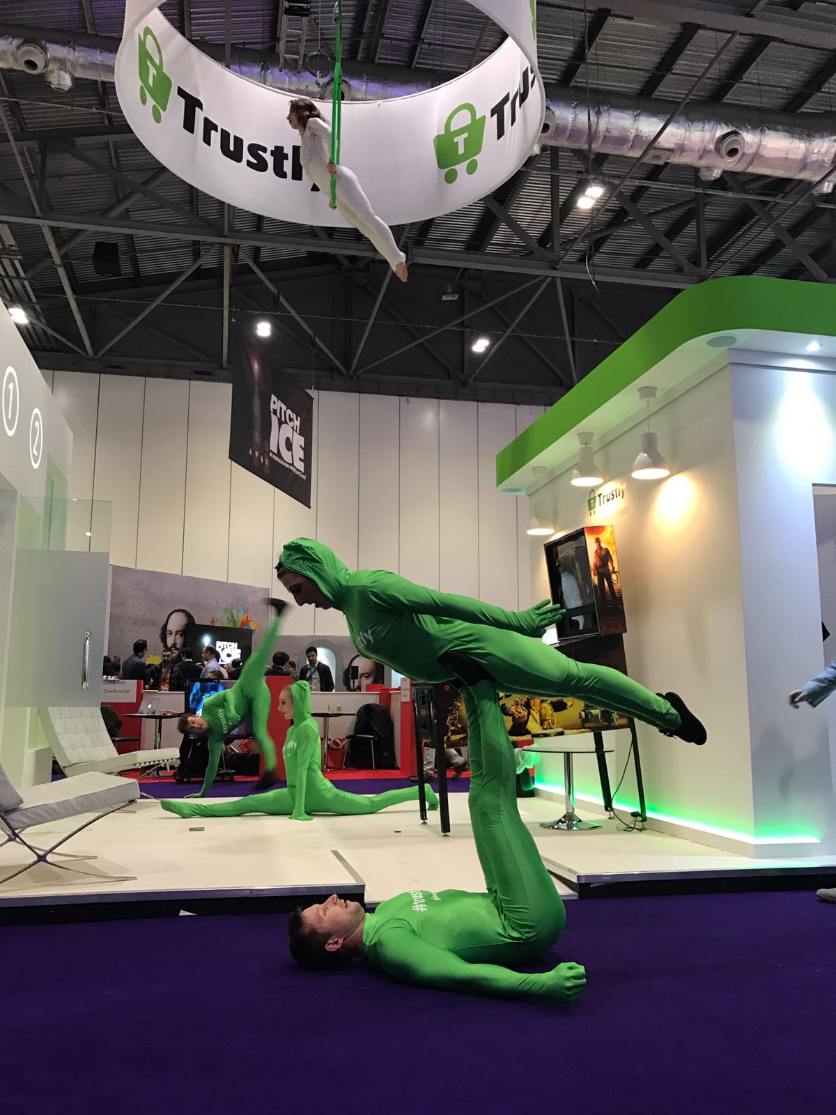 Acrobats and circus acts in green suits perform on exhibition stand