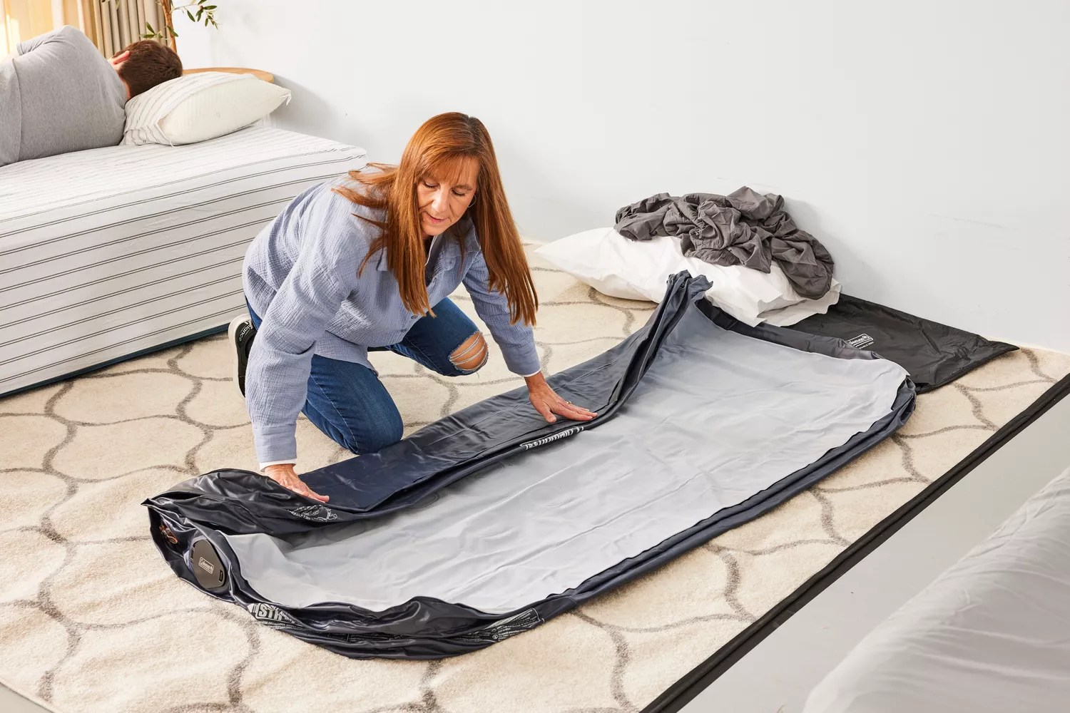 A person folds up the Coleman SupportRest Double-High Rechargeable Air Mattress