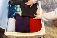 A person putting clothing inside of the IKEA SKUBB Storage case