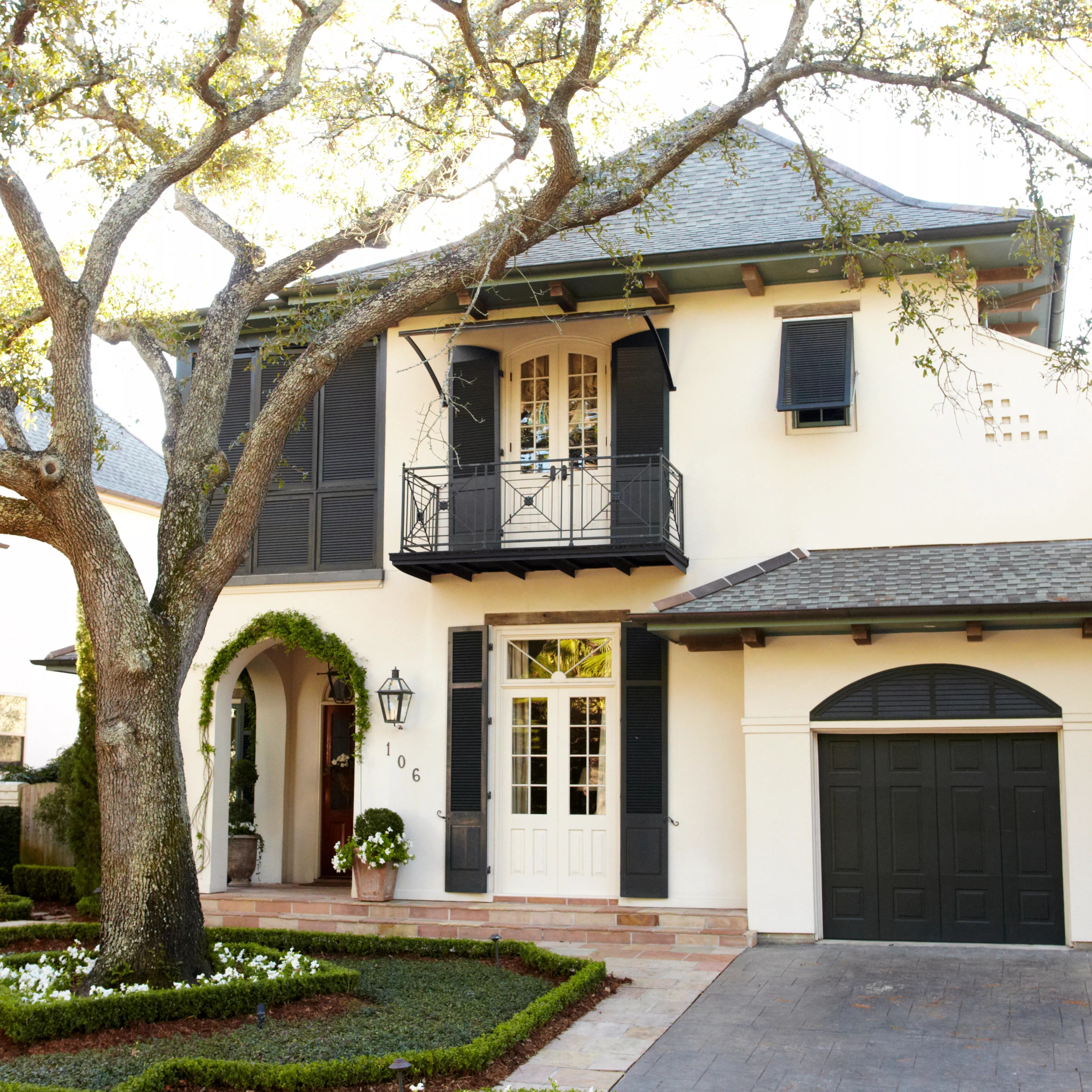 Two story tuscan style house with black accents and stucco siding.