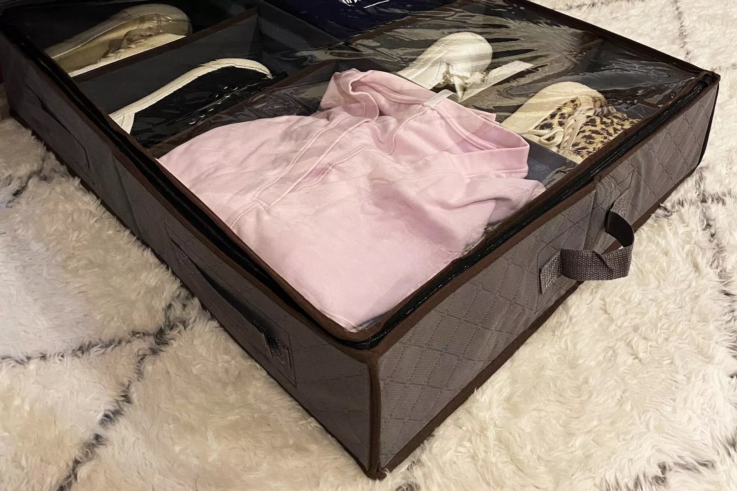 The Anyoneer Under Bed Shoe Storage Organizer filled with accessories on a pattern rug