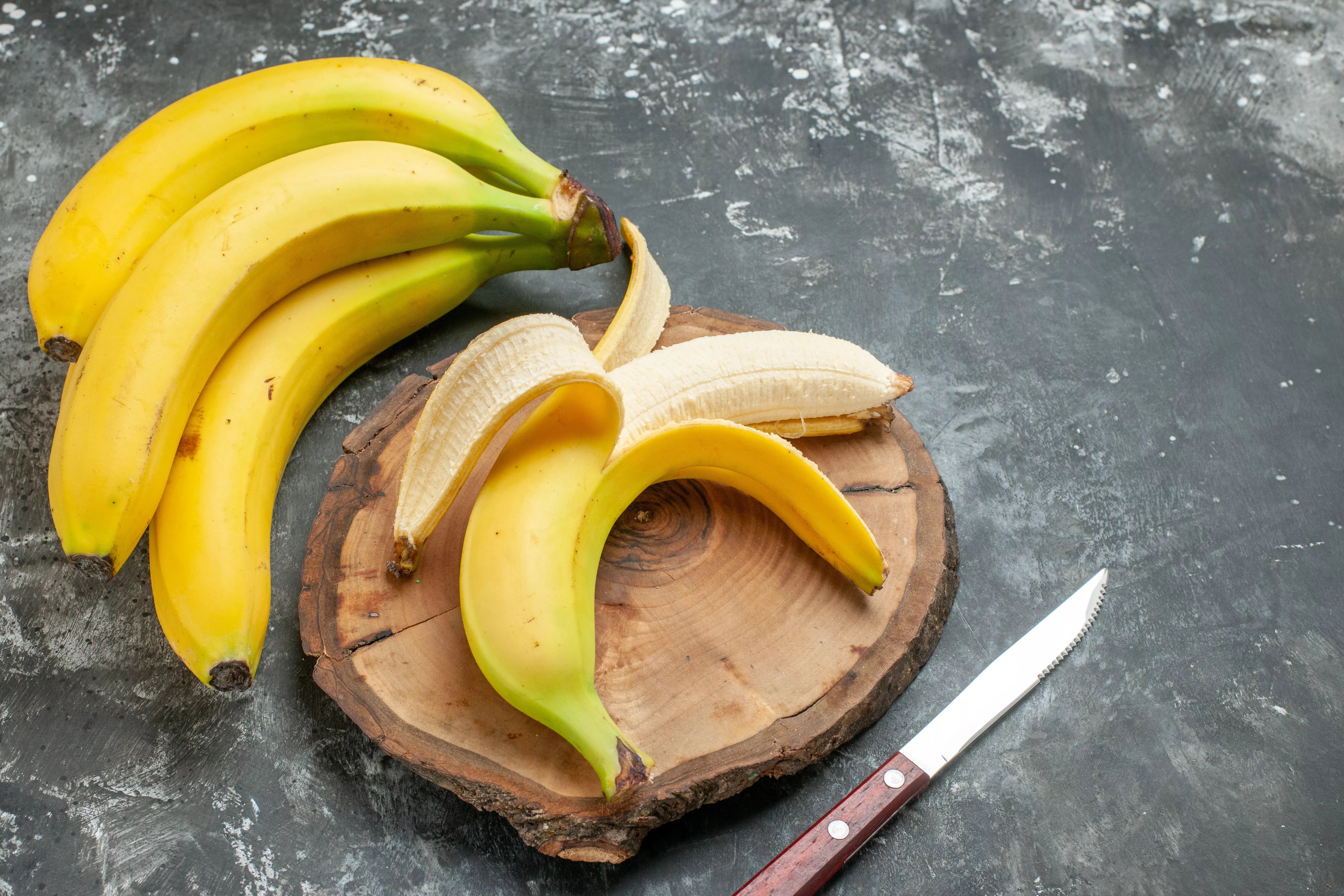 peeled banana and bunch of bananas on counter