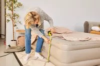 A person measures the Insta-Bed Raised 18-in Queen Pillow Top Air Mattress &amp; Internal Never Flat Pump