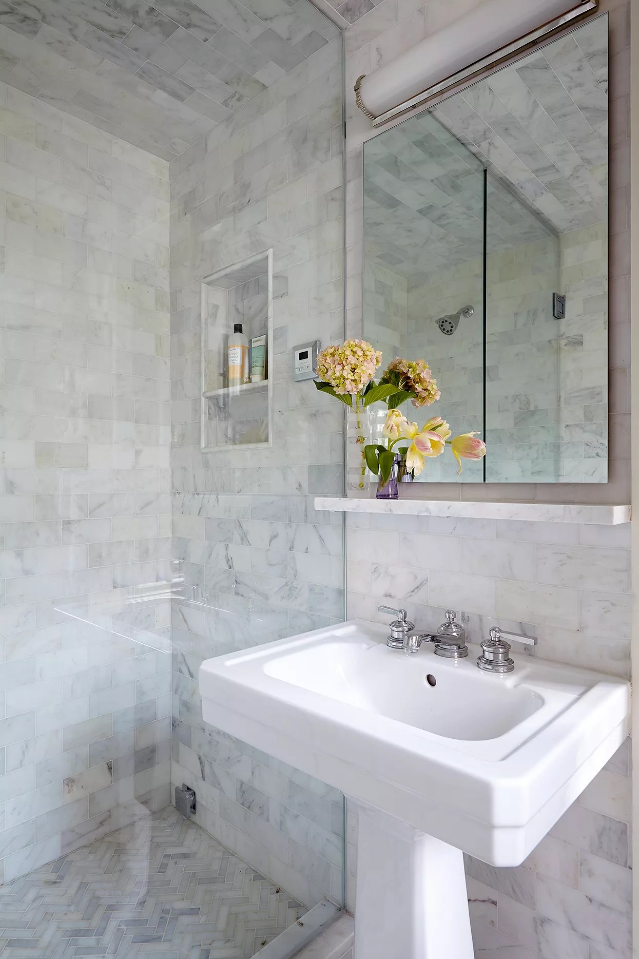 pedestal sink under toiletry ledge next to marble shower