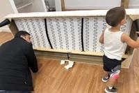 A child and adult inspect the bottom of the IKEA Uppland Sofa