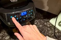 A person presses a button on the PowerXL Vortex Pro Air Fryer