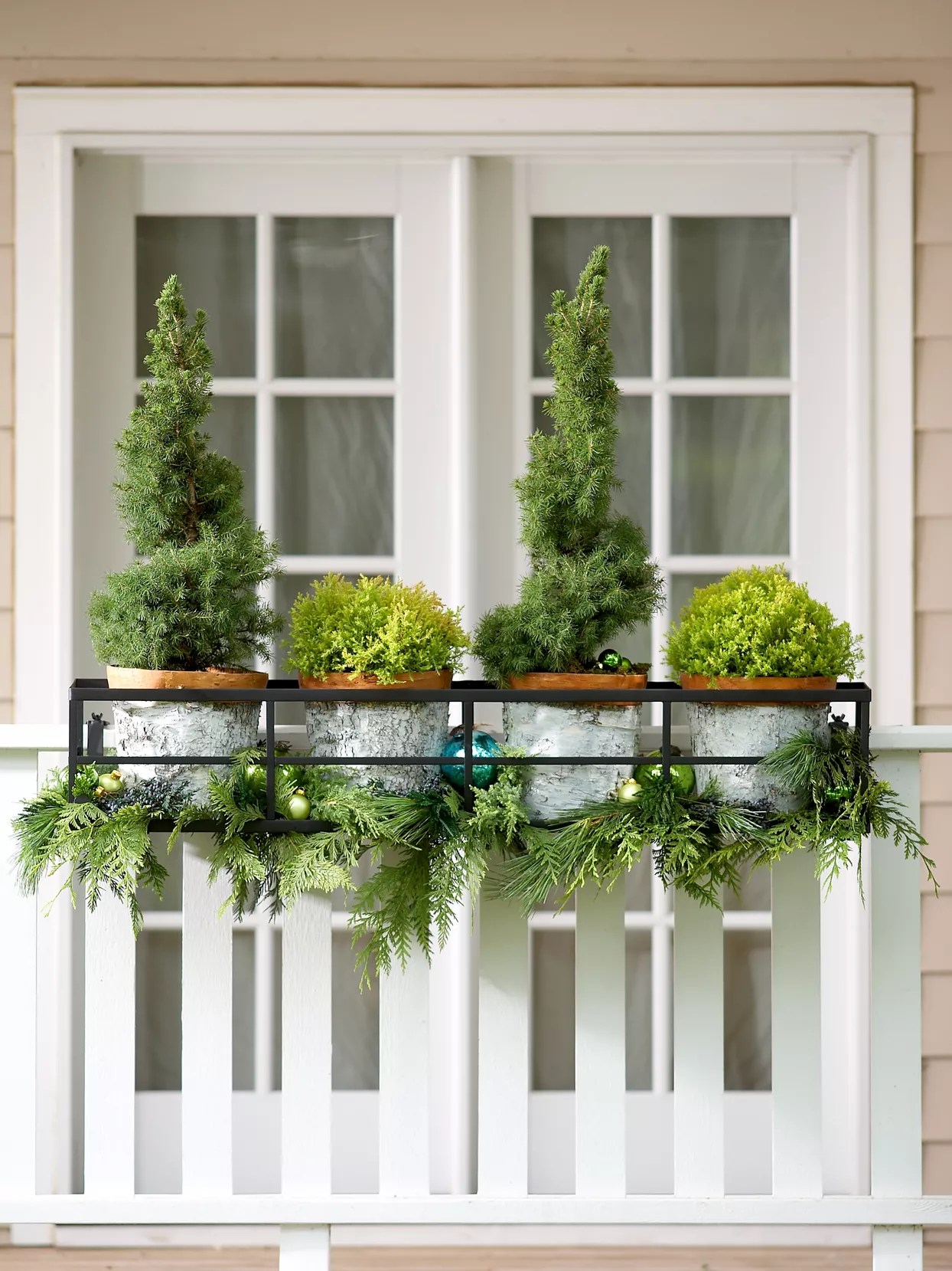 potted evergreens holiday decoration on porch railing