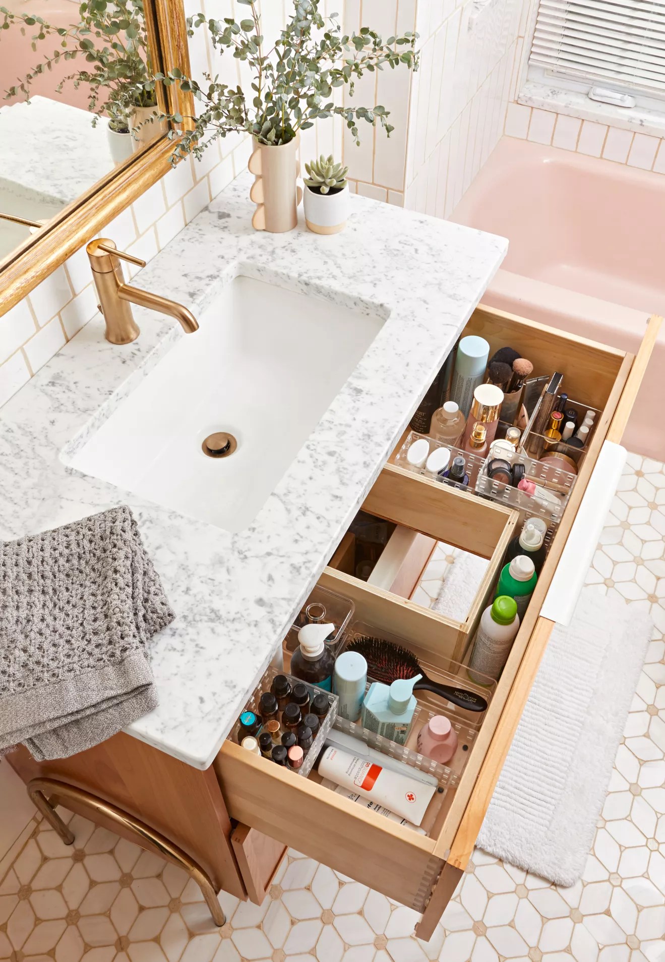 bathroom drawer open under white marble counter