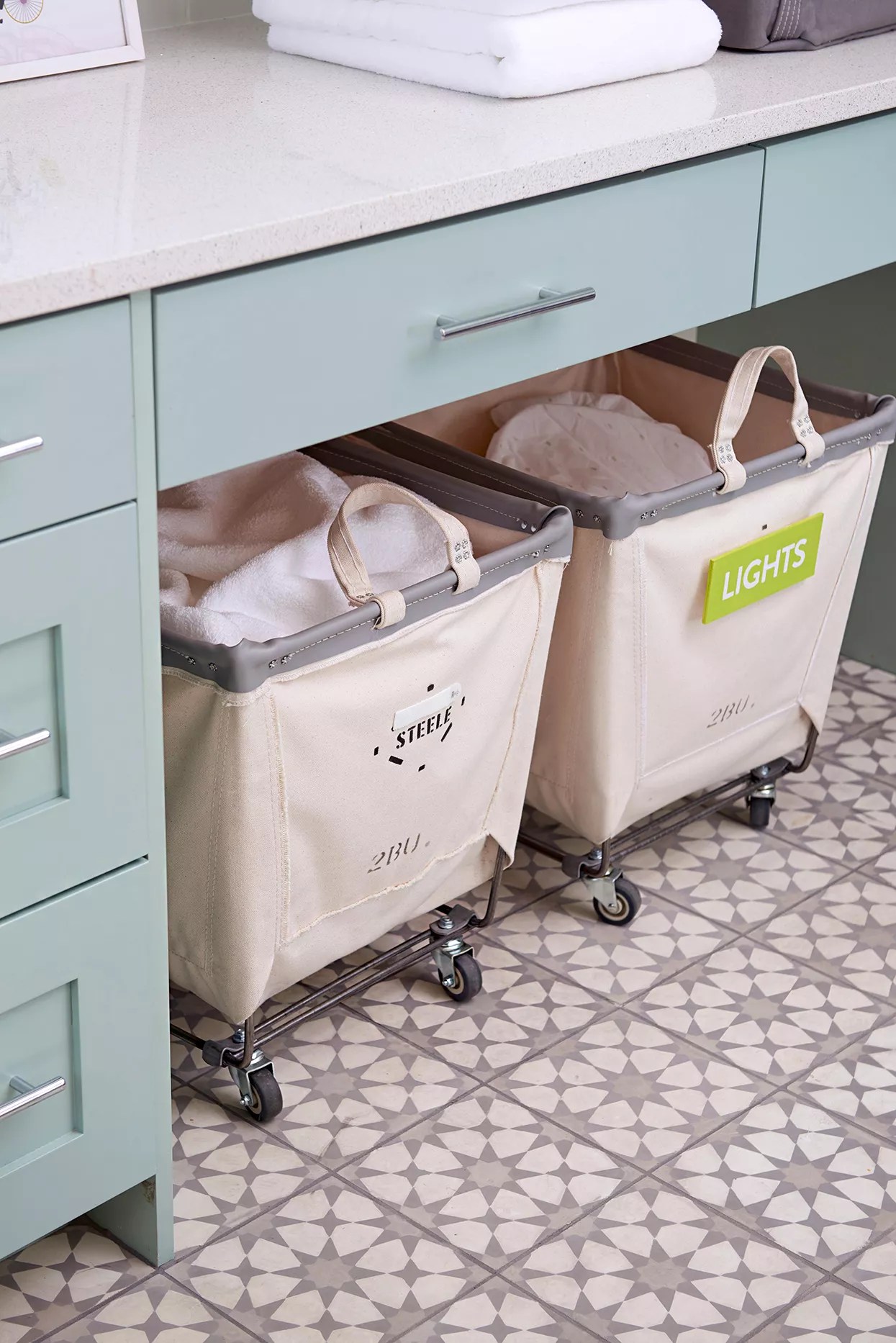 labeled bins with rollers underneath laundry room counter
