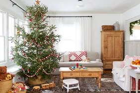 christmas tree with red and white pom garland in neutral living room